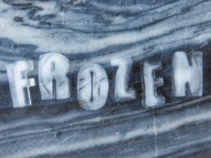 The word frozen spelled out in ice letters on a frosty surface