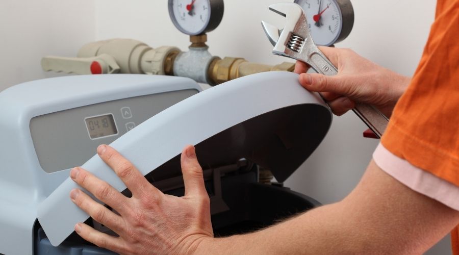 Person using a wrench to work on a whole home water softener