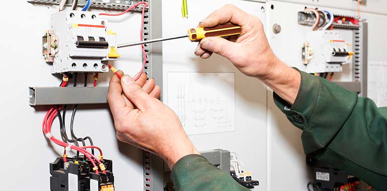 A technician's hands upgrading an electrical panel.