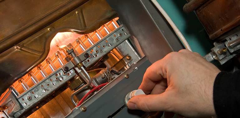 Plumber's hand repairing a tankless water heater system.