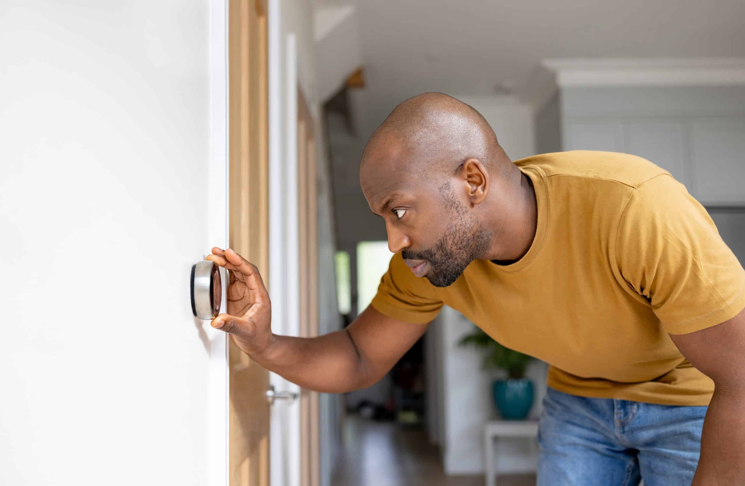 Man adjusting the temperature on the thermostat of his house